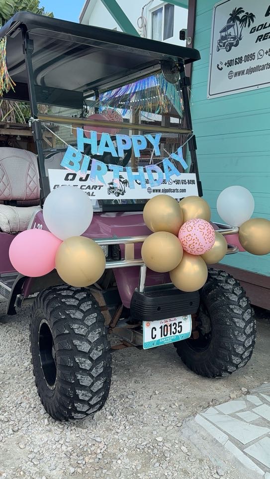 Closeup of a decorated golf cart with birthday balloons and personalized name sign in San Pedro Belize