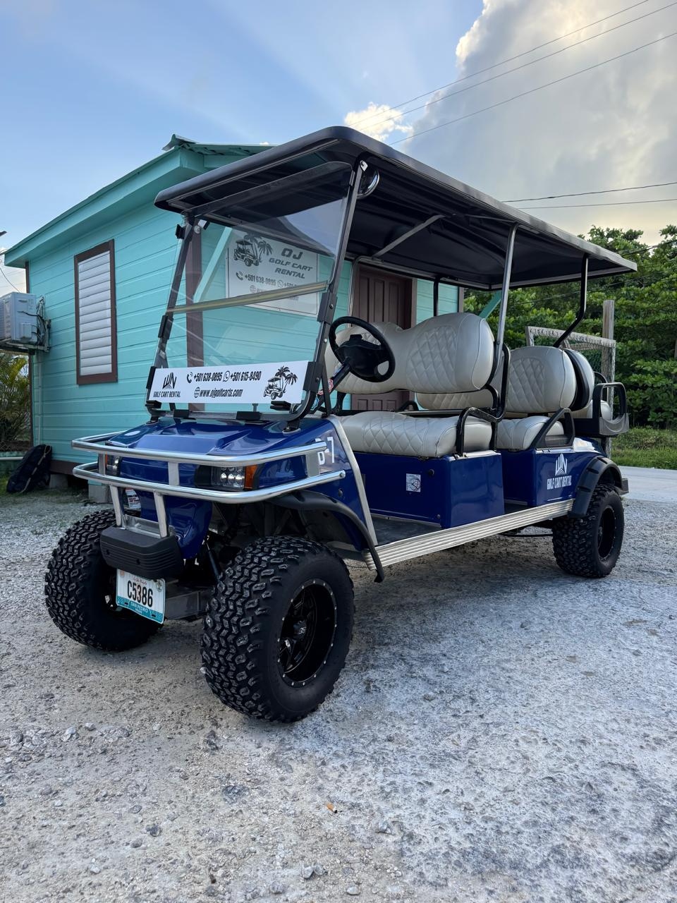 6-person golf cart rental in San Pedro Belize — navy blue with large off-road tires and tan leather seats